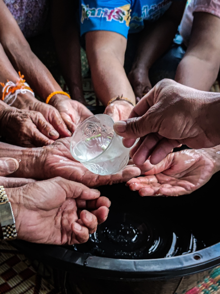 A hand pours water over many hands above a basin A hand pours water over many hands above a basin