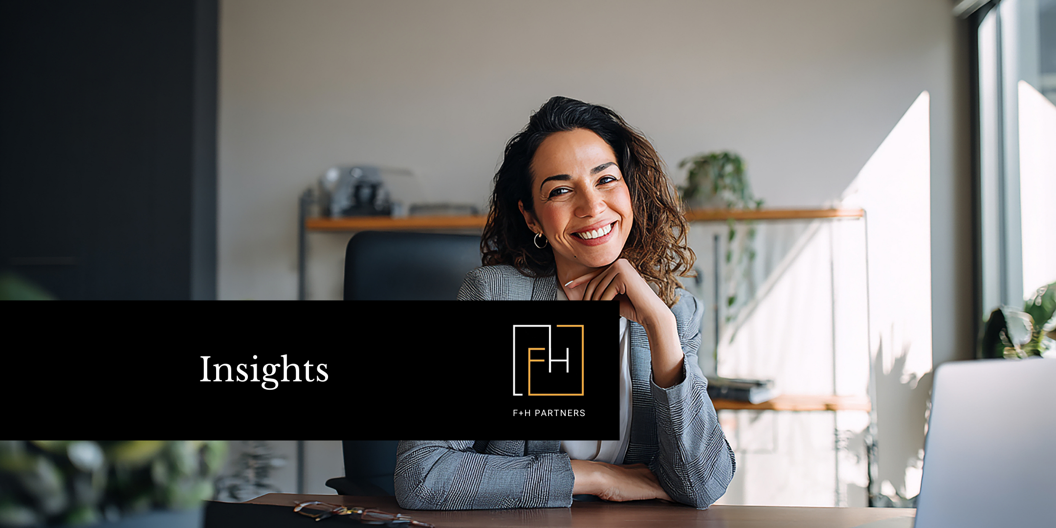 Smiling professional seated at a desk in a modern office, representing nonprofit leadership and the executive search for key organizational roles.